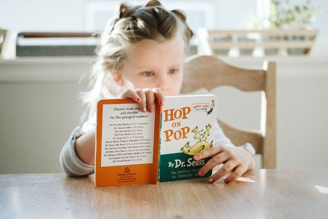 Niña leyendo un cuento sentada eu na mesa